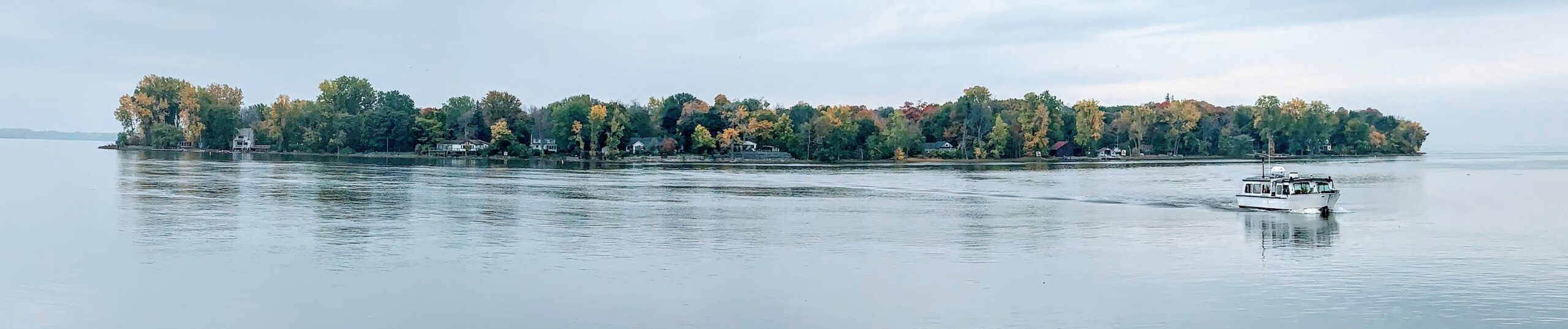 Panoramic view of Dorval Island in the St. Lawrence River, with the ferry crossing toward shore.